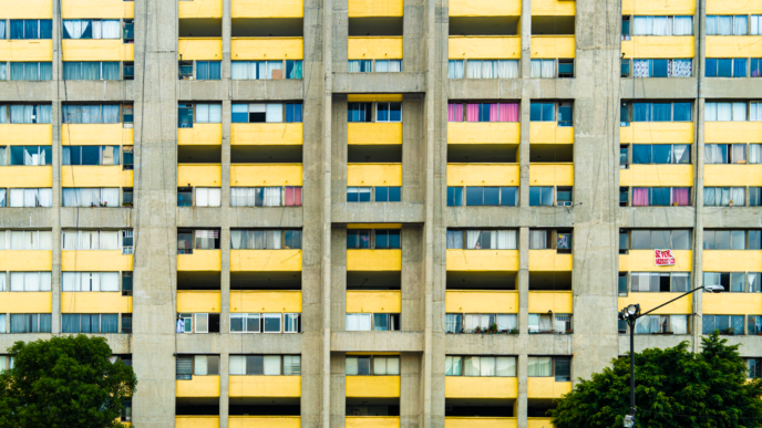 Concrete apartment building with striking yellow balconies in Mexico City, showcasing urban residential life.