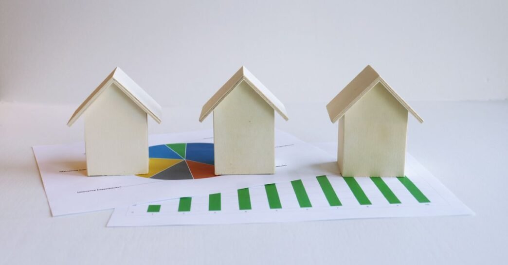 Wooden model houses on graphs depict real estate market analysis and trends.