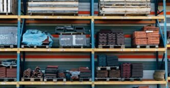 Shelves filled with construction materials like tiles and wood pallets in a warehouse setting.
